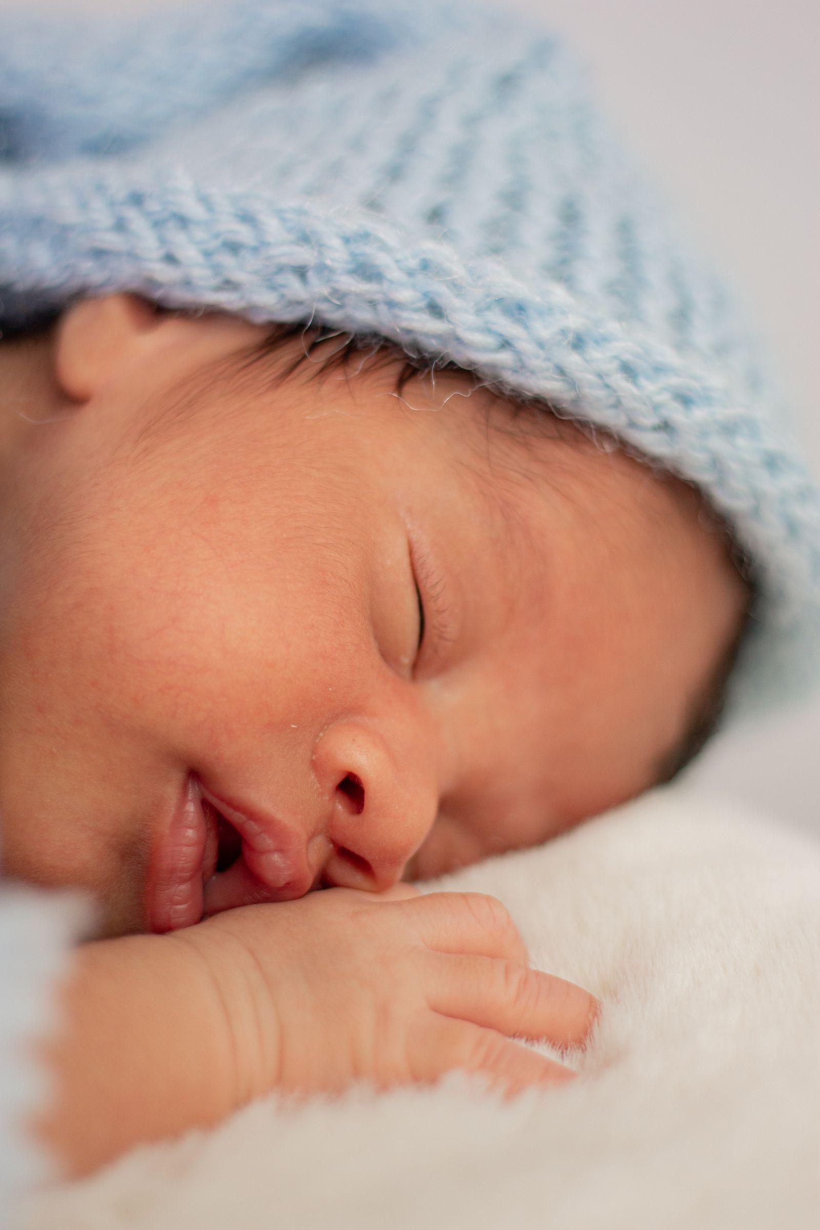 A newborn sleeping soundly under a soft knitted blanket
